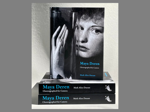 stack of books with cover shown of Deren and hand distorted through glass