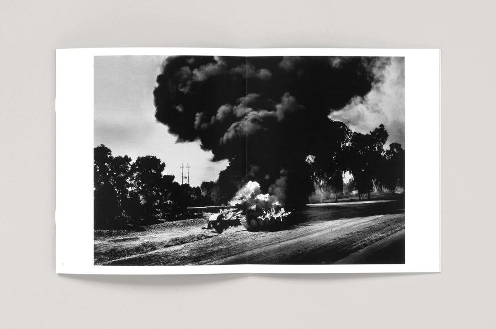 Black and white photograph of a train wreck with smoke billowing into the sky.