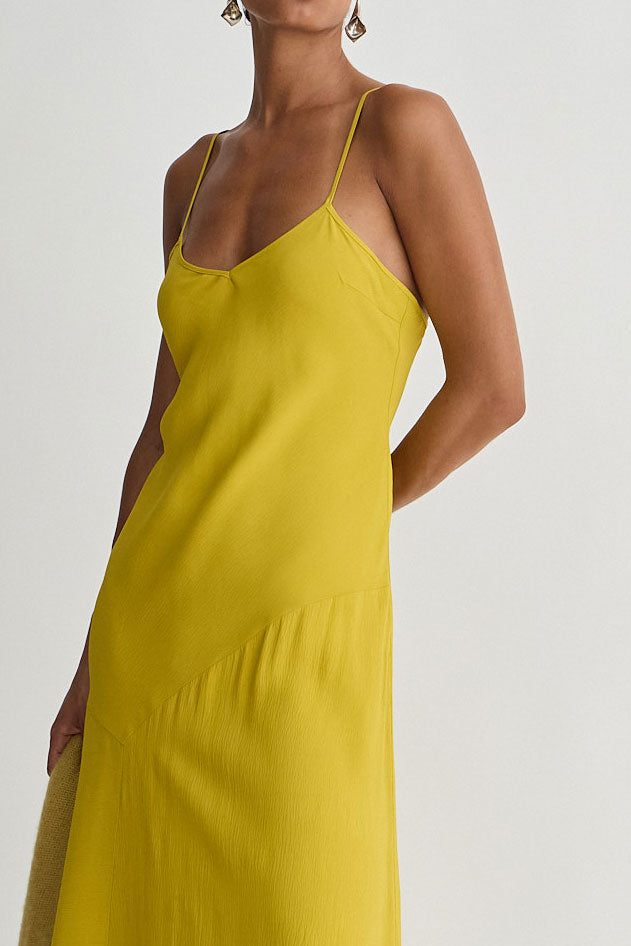 Yellow slip dress worn by a model on a white background