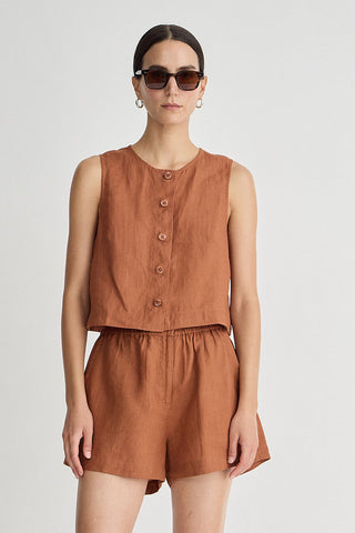 Woman wearing a brown sleeveless top and shorts set on a white background