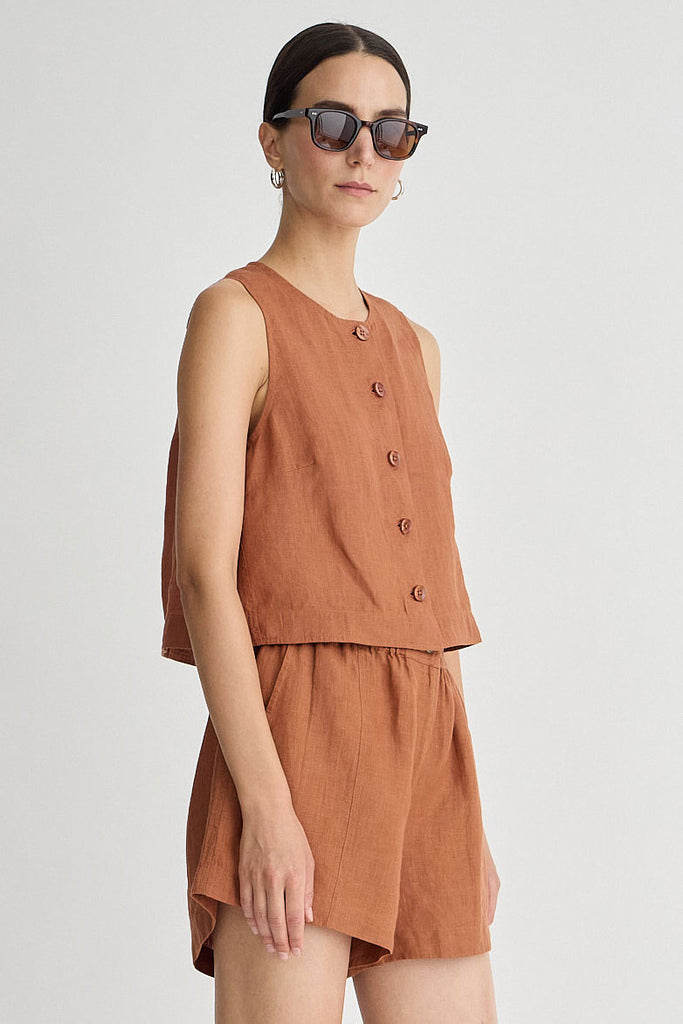 Woman wearing a brown sleeveless top and shorts set on a white background