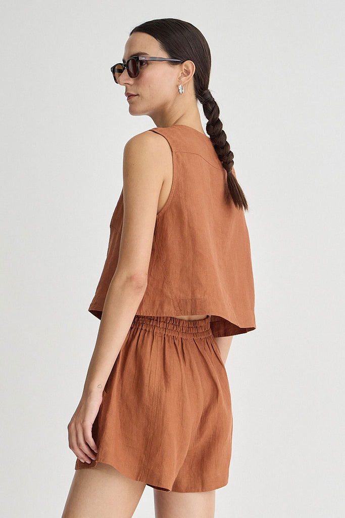 Woman wearing a brown sleeveless top and shorts set on a white background