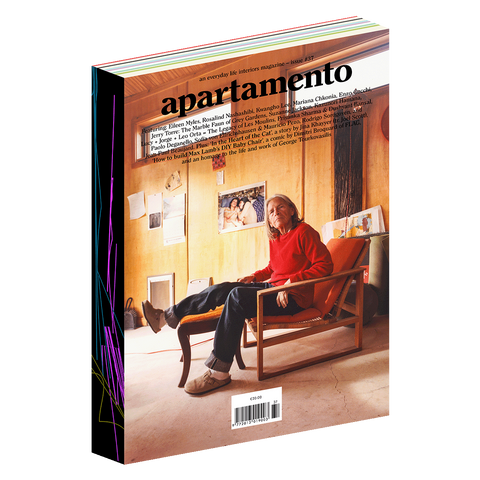Picture of Apartamento magazine showing person sitting on chair in red sweater and blue pants with text on top of page