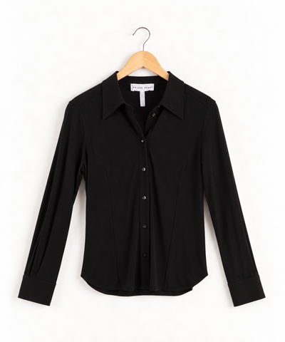 Apiece Apart black long-sleeve button-down blouse hanging on a wooden hanger. The shirt features a pointed collar and vertical tailored seams down the front.