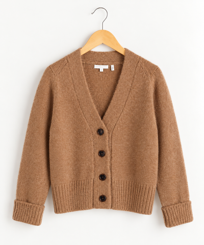 Camel colored cardigan with brown buttons on wooden hanger against white wall