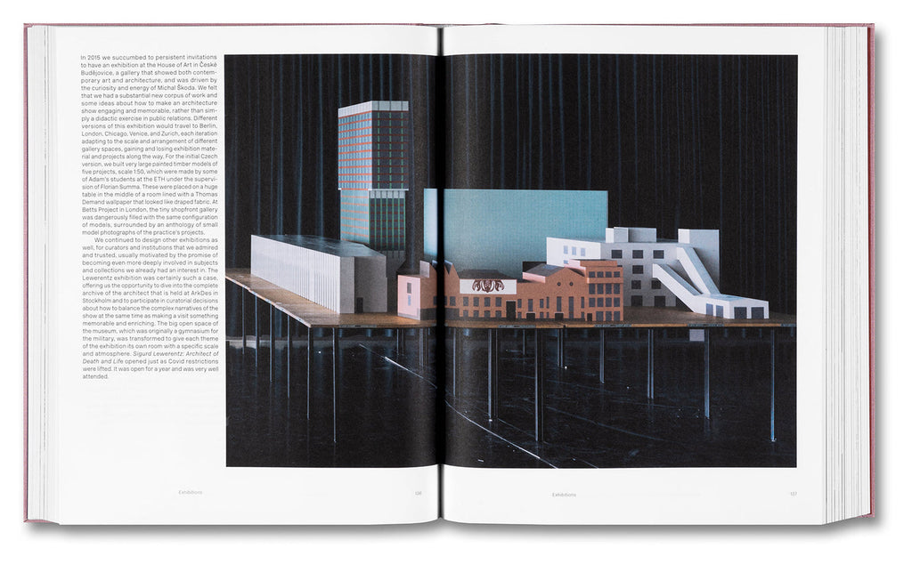 Open book showing architectural models on a table with text on the left page.