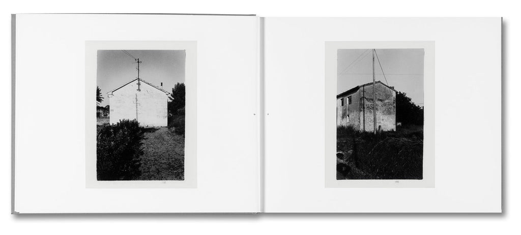 Black and white photo album open to two pages showing small buildings.