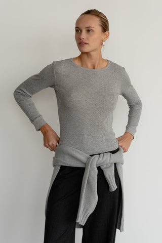 A person wearing a heather grey, long-sleeved thermal top with a boat neckline and ribbed sleeves.