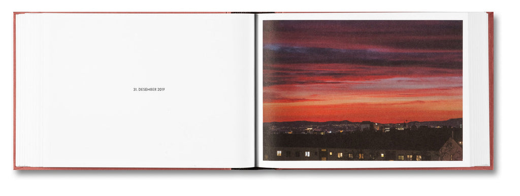 Open book showing a page with a red and orange sunset over a cityscape.