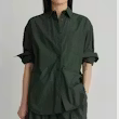 A dark olive green button-up shirt with rolled-up sleeves, worn by a model against a plain light gray background.