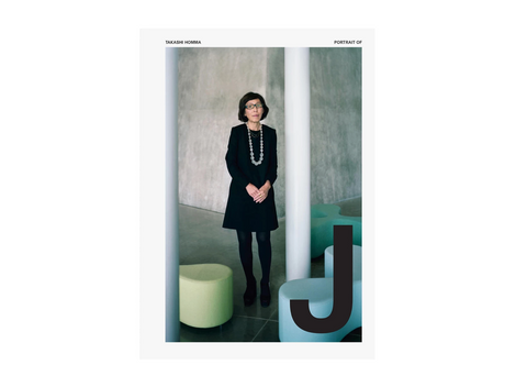 A portrait photograph of a woman standing indoors between two white columns, wearing a black dress, black tights, and a long pearl necklace. The photo is presented with a white border and small text at the top reading 'TAKASHI HONMA' and 'PORTRAIT OF'.