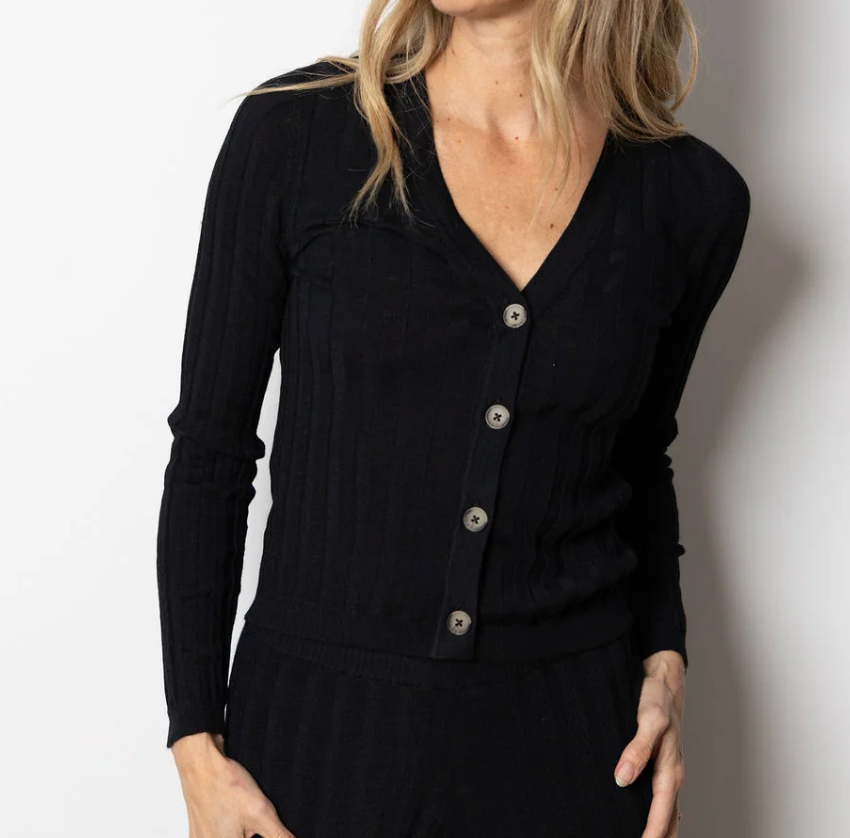 A woman wearing a black ribbed long-sleeve cardigan with a V-neck and silver buttons, shown from the shoulders to the hips against a plain light background.