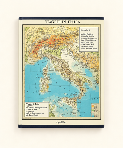 Front cover of Viaggio in Italia, an Italian photography book featuring a vintage map of Italy in blue, green, and yellow, with black serif typography, published by Quodlibet, photographed against a warm cream background.