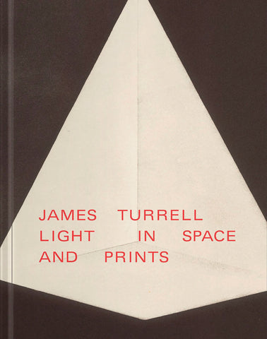 Book cover featuring a large white geometric shape resembling a glowing pyramid or folded paper form against a dark brown-black background. Red uppercase text across the center reads: “JAMES TURRELL LIGHT IN SPACE AND PRINTS.”