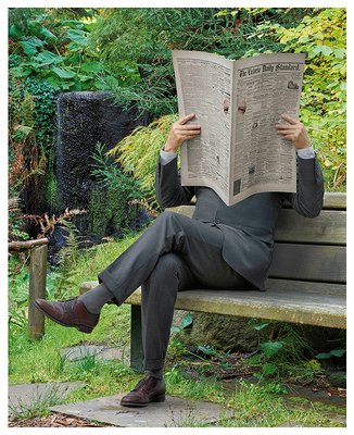 person sitting on bench reading newspaper